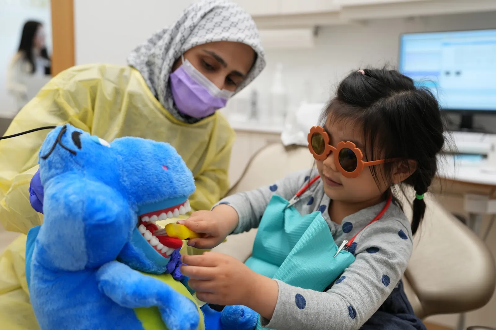 Dental team using a plush toy to show a child what to expect during their visit, DTC Dental Treatment Center, Richmond BC
