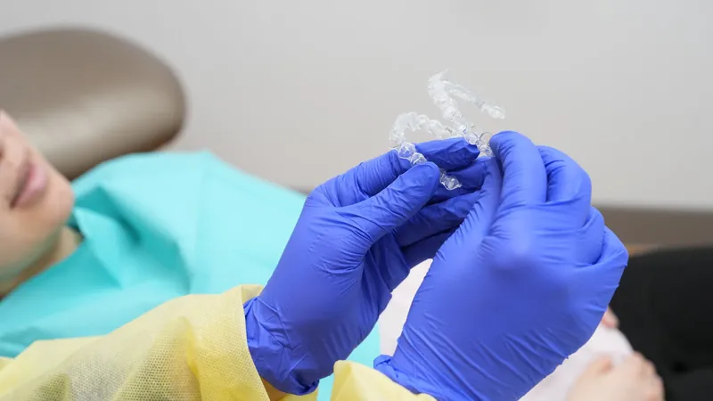 Team member holding a pair of clear aligners next to a patient at DTC Dental Treatment Center in Richmond, BC