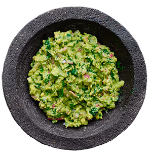 Bowl of fresh green guacamole with visible herbs and diced onions.