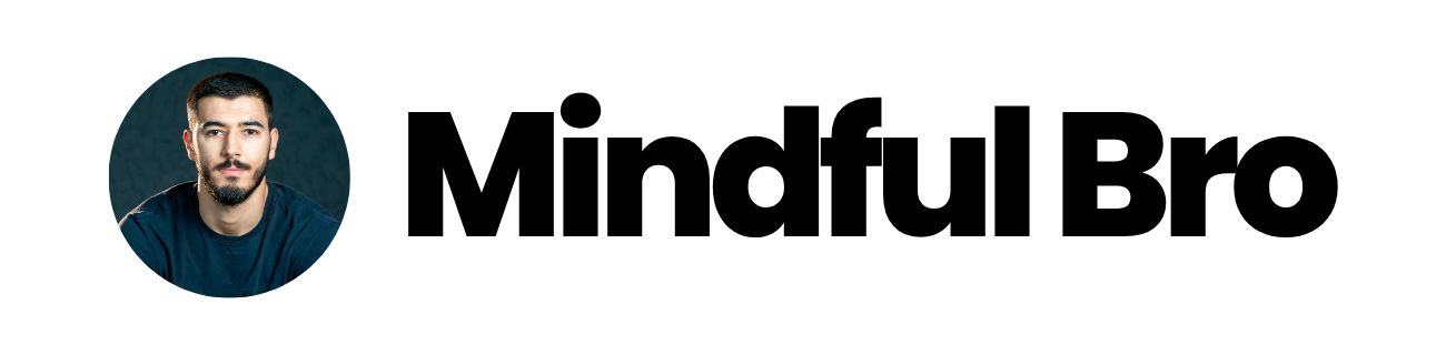 Headshot of a man with dark hair, beard, and blue shirt against a dark background.