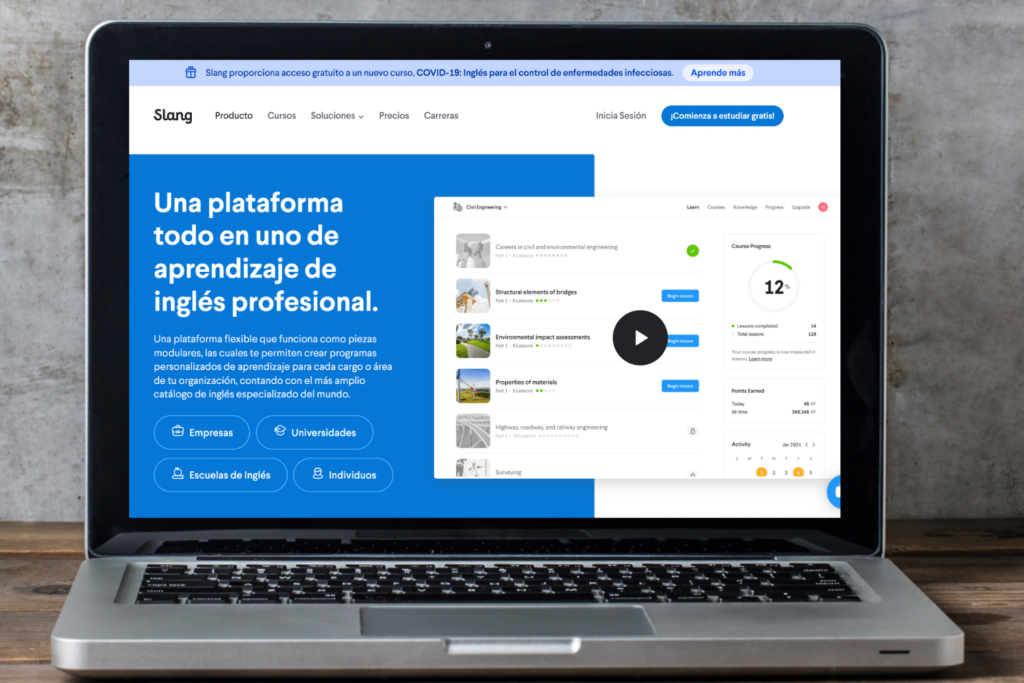 Una computadora portátil plateada está encima de una mesa de madera. En la pantalla, se puede ver la página de inicio de Slang.