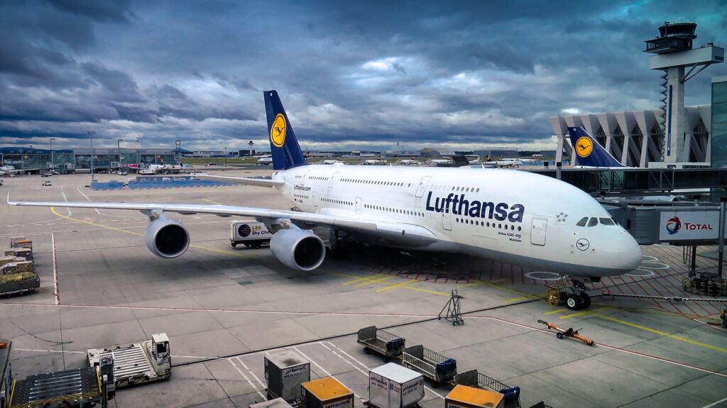 Um avião está em uma pista de aeroporto e conectado à passarela de embarque dos passageiros.