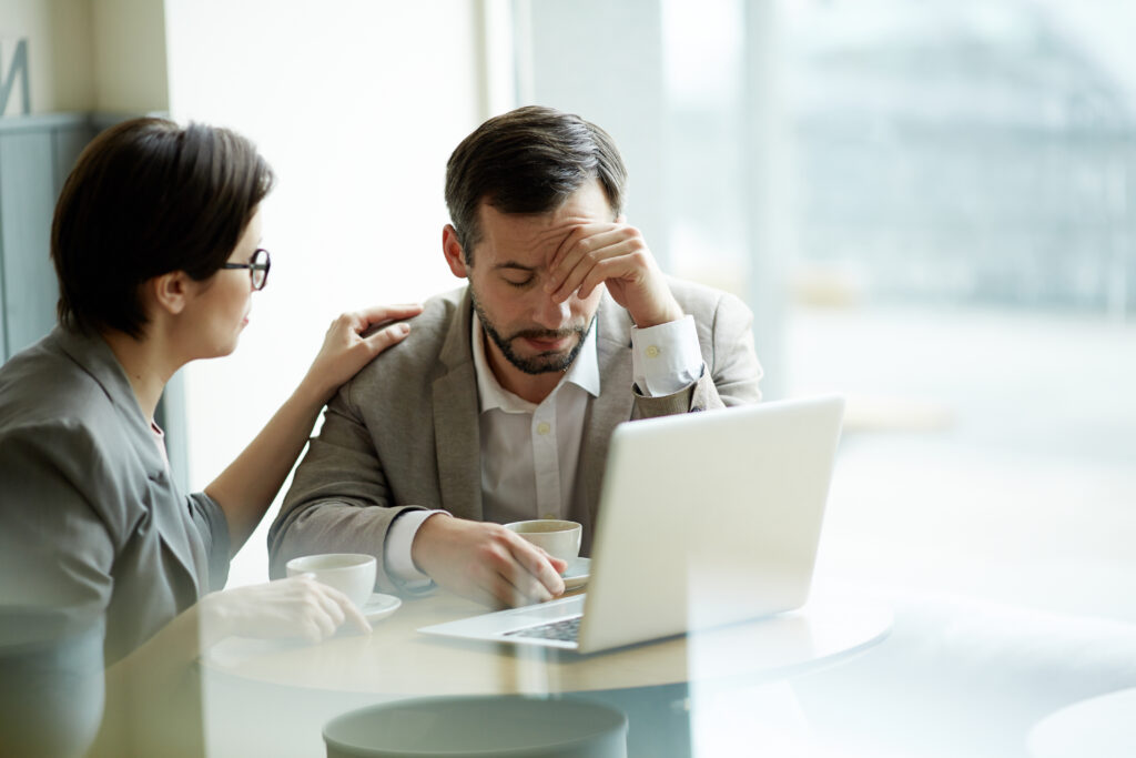 Mulher segurando o ombro de um colega de trabalho preocupado.