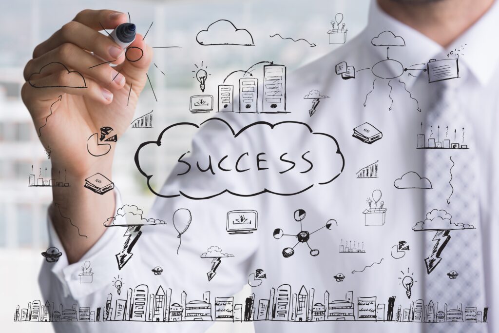 Em um quadro, um homem escreve “success” no meio junto a alguns desenhos.