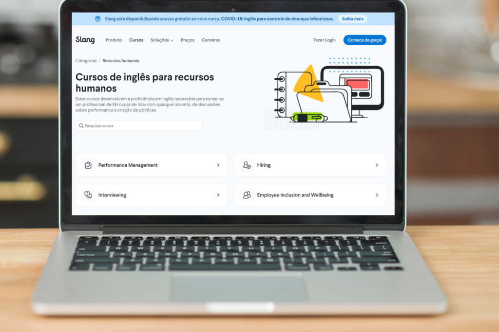 Laptop aberto, sobre uma mesa de madeira, na área de cursos de inglês para recursos humanos da Slang com abas como “Performance Management”, “Interviewing”, “Hiring” e “Employee Inclusion and Wellbeing”.