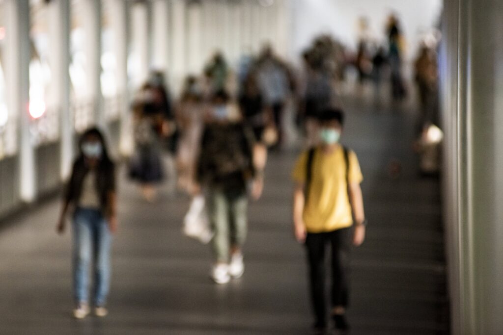 Multidão desfocada usando máscaras em uma passagem.