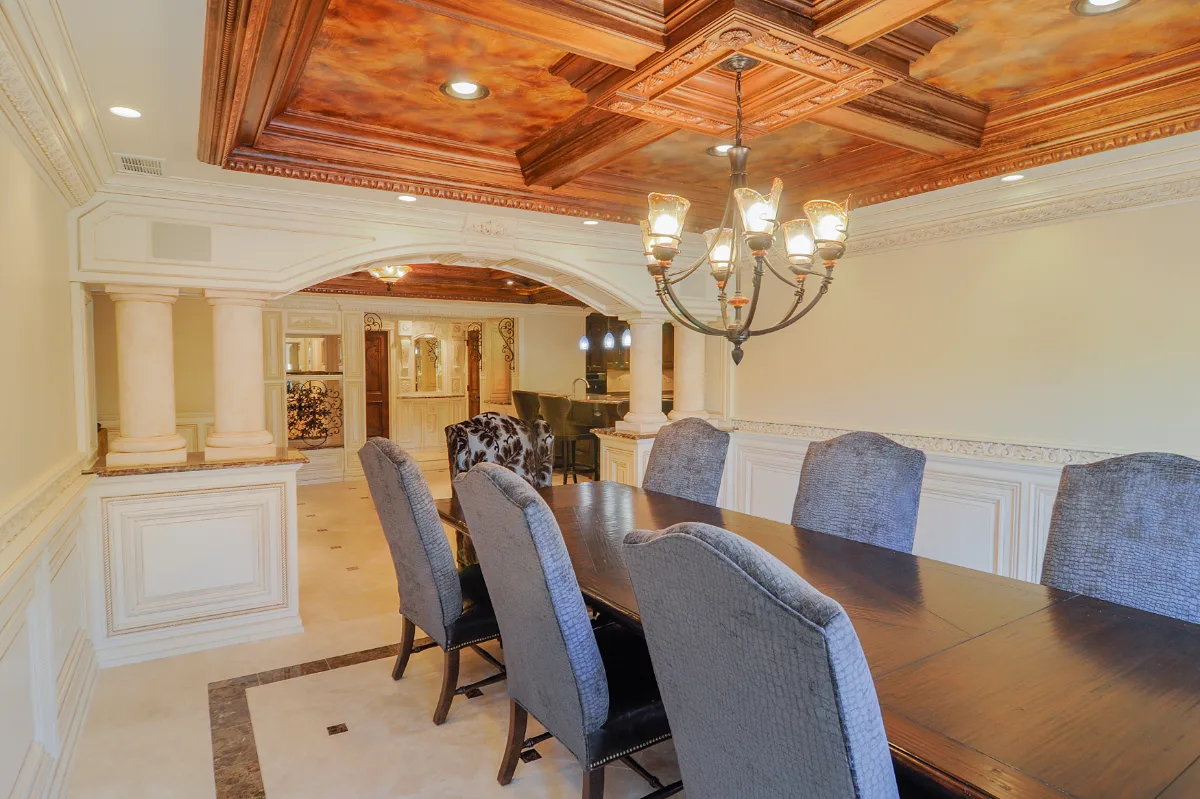 A traditional-intricate basement remodel in Franklin, TN. Coffered ceiling, custom carpentry, built-in entertainment unit, fireplace, bar, guest bath, gym, and dining room by Sebring Design Build.