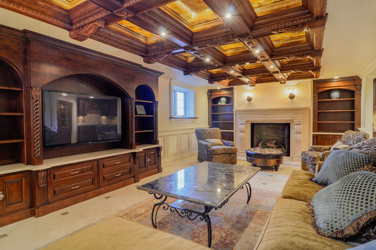 A traditional-intricate basement remodel in Franklin, TN. Coffered ceiling, custom carpentry, built-in entertainment unit, fireplace, bar, guest bath, gym, and dining room by Sebring Design Build.