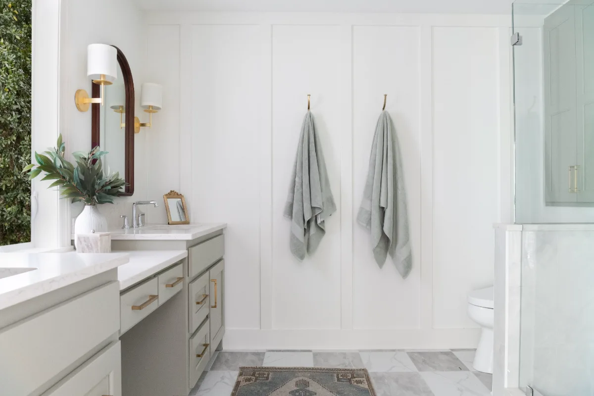 A modern-soft-luxurious primary bath in Leiper's Fork, TN 37069. CWP Mourning Dove Standard Overlay cabinetry, Metro Quartz Mystique scalloped countertops, Delta Chrome fixtures, and Carrera White 13x13 porcelain floor tile by Sebring Design Build.