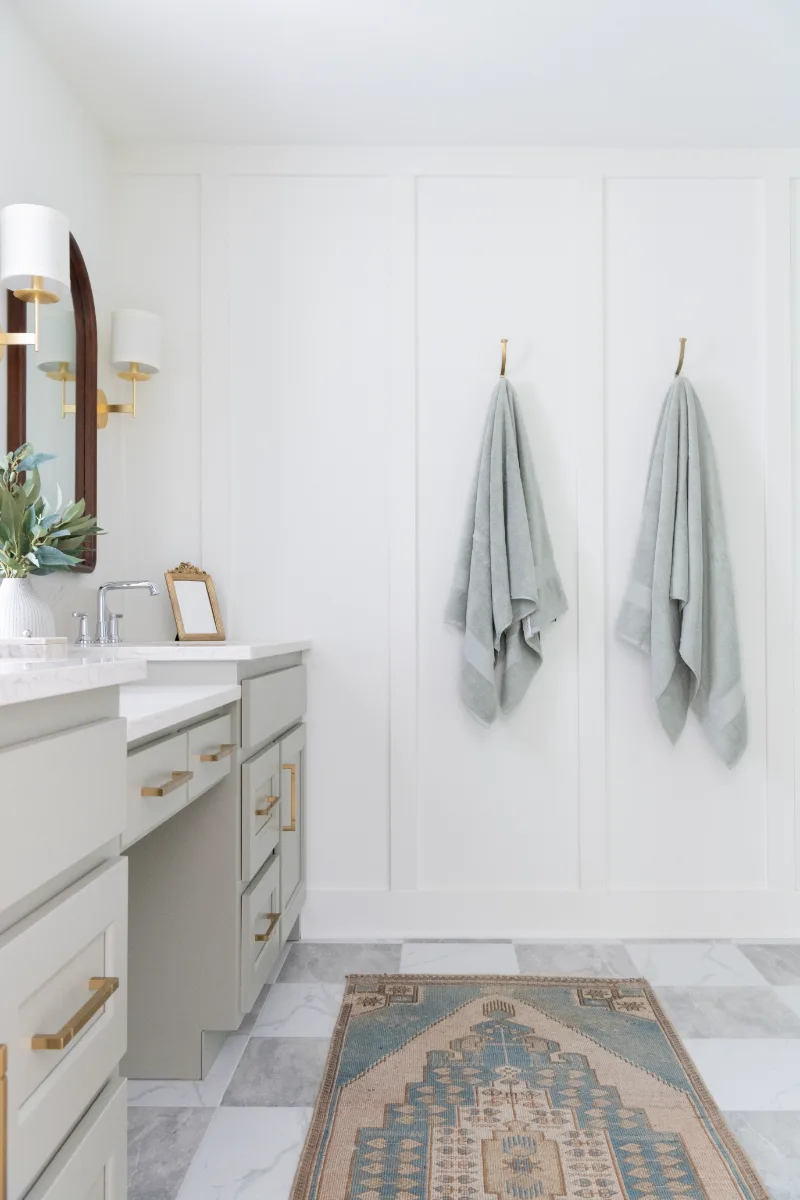 A modern-soft-luxurious primary bath in Leiper's Fork, TN 37069. CWP Mourning Dove Standard Overlay cabinetry, Metro Quartz Mystique scalloped countertops, Delta Chrome fixtures, and Carrera White 13x13 porcelain floor tile by Sebring Design Build.