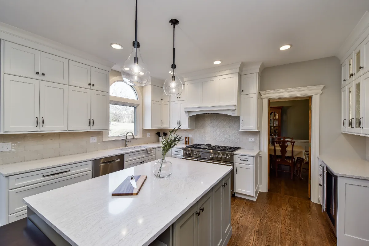 A transitional-refined kitchen in Franklin, TN. CWP Soft White and Tarragon Classic Square Recessed cabinetry, Cambria Ironsbridge Polished quartz, Delta Cassidy Polished Nickel faucet, and Sonoma Stellar Bossy Gray backsplash by Sebring Design.