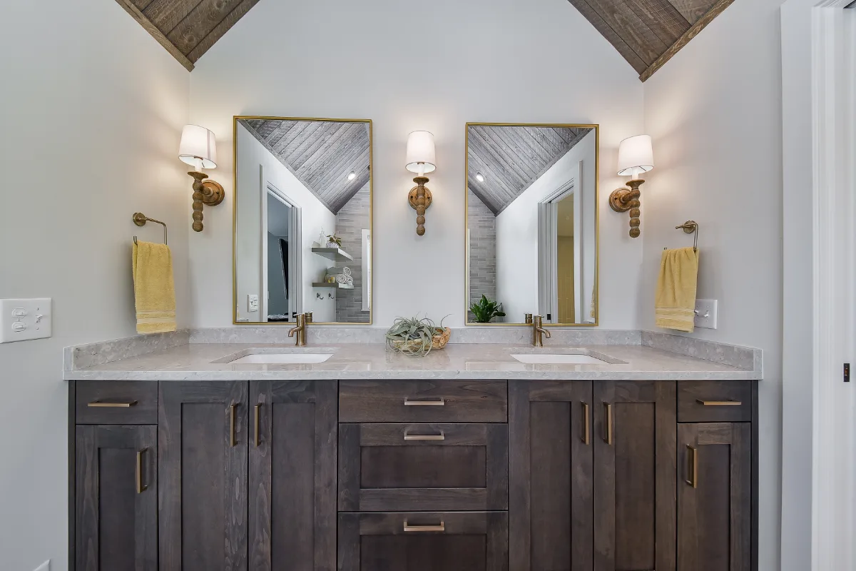 A rustic-warm primary bath in Franklin, TN. Bellmont Alder Folkstone cabinetry with Griege floating shelves, Orion Blanco Mist quartz, Delta Trinsic Champagne Bronze, Kohler Sunstruck tub, and Cassettone Honey Nut wood-look floor tile by Sebring.