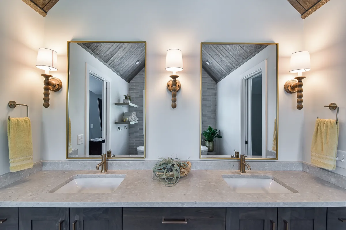 A rustic-warm primary bath in Franklin, TN. Bellmont Alder Folkstone cabinetry with Griege floating shelves, Orion Blanco Mist quartz, Delta Trinsic Champagne Bronze, Kohler Sunstruck tub, and Cassettone Honey Nut wood-look floor tile by Sebring.