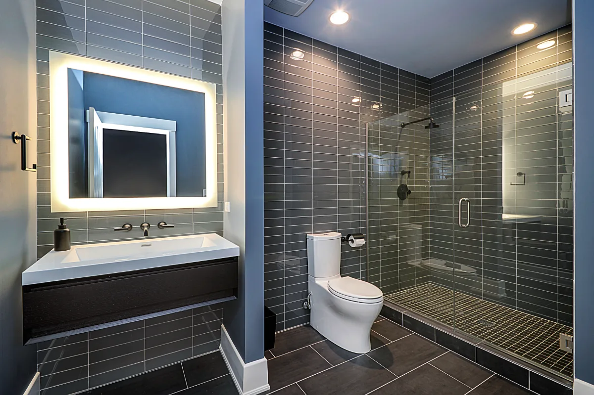 A modern-masculine guest bath in a Brentwood, TN basement remodel. Glass-enclosed shower, dark vanity, and clean geometric tile lines by Sebring Design Build.