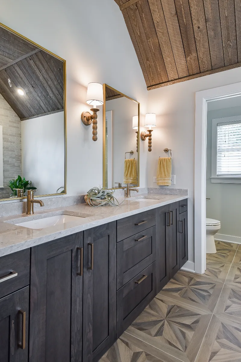 A rustic-warm primary bath remodel in Franklin, TN. Bellmont Alder Folkstone cabinetry, Orion Blanco Mist quartz, Delta Trinsic Champagne Bronze, Kohler Sunstruck tub, and Cassettone Honey Nut wood-look floor tile by Sebring Design Build.