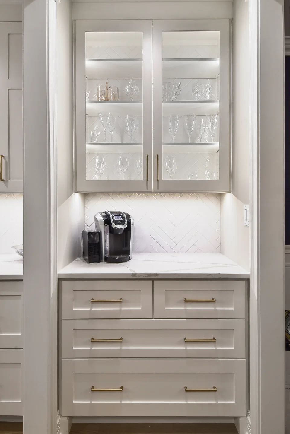 A modern-elegant home bar in Brentwood, TN. Ebony Shaker cabinetry, Corian Quartz Calcutta Natural, and Kohler Vibrant Brushed Moderne Brass by Sebring Design Build.