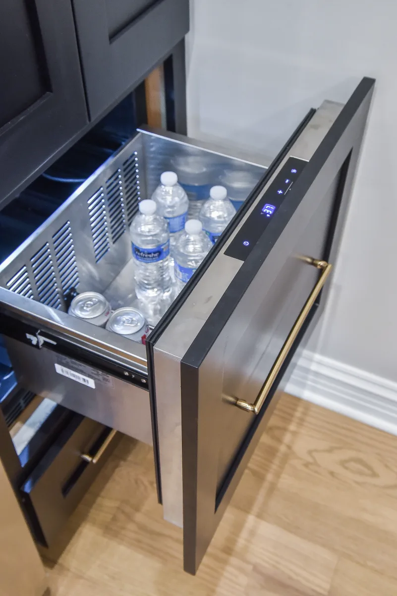 A modern-elegant home bar in Brentwood, TN. Ebony Shaker cabinetry, Corian Quartz Calcutta Natural, and Kohler Vibrant Brushed Moderne Brass by Sebring Design Build.