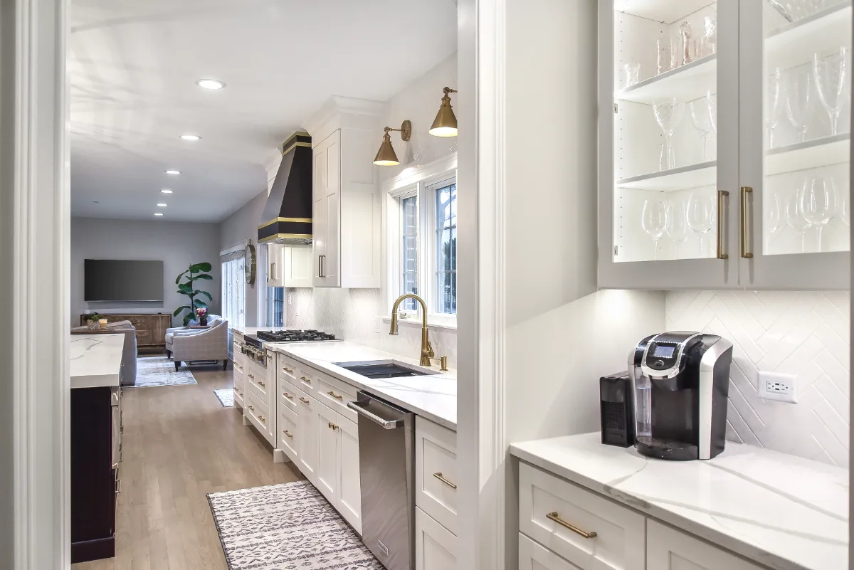 A modern-elegant home bar in Brentwood, TN. Ebony Shaker cabinetry, Corian Quartz Calcutta Natural, and Kohler Vibrant Brushed Moderne Brass by Sebring Design Build.