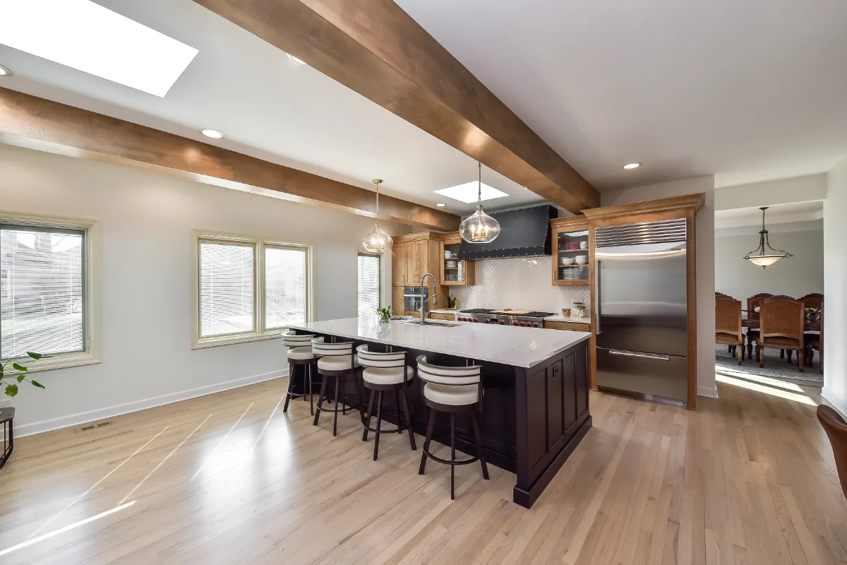 A modern-rustic dining room in Brentwood, TN connected to an open-concept kitchen remodel. Warm Fruitwood and Bunker Hill Black material continuity by Sebring Design Build. Specs pending photo verification.