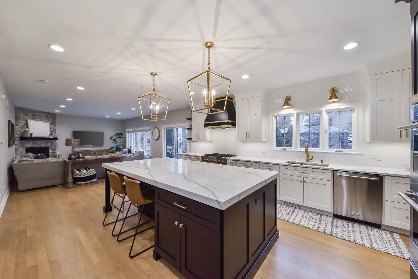 A modern-elegant kitchen in Brentwood, TN. Paint-grade Ebony and Soft White Shaker cabinetry, Corian Quartz Calcutta Natural, Kohler Vibrant Brushed Moderne Brass faucet, and Crafted Snow Gloss 2x10 backsplash by Sebring Design Build.