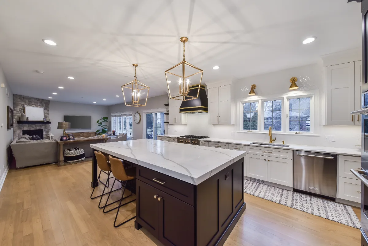 A modern-elegant kitchen in Brentwood, TN. Paint-grade Ebony and Soft White Shaker cabinetry, Corian Quartz Calcutta Natural, Kohler Vibrant Brushed Moderne Brass faucet, and Crafted Snow Gloss 2x10 backsplash by Sebring Design Build.