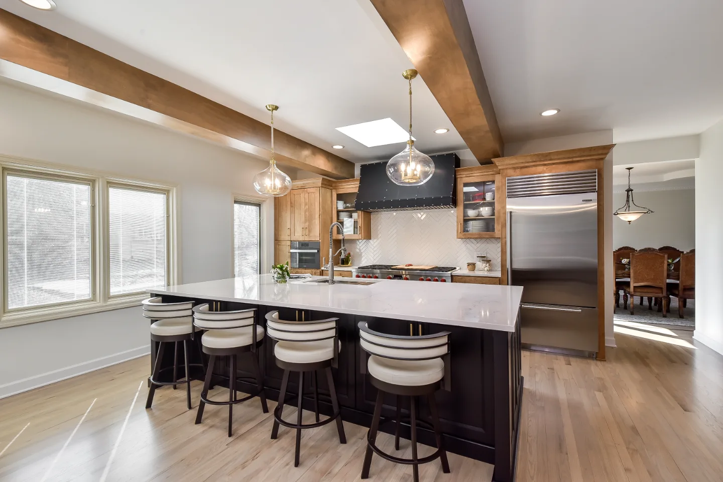 A modern-rustic dining room in Brentwood, TN connected to an open-concept kitchen remodel. Warm Fruitwood and Bunker Hill Black material continuity by Sebring Design Build. Specs pending photo verification.