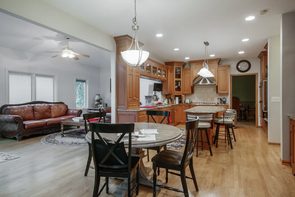 A modern-rustic dining room in Brentwood, TN connected to an open-concept kitchen remodel. Warm Fruitwood and Bunker Hill Black material continuity by Sebring Design Build. Specs pending photo verification.