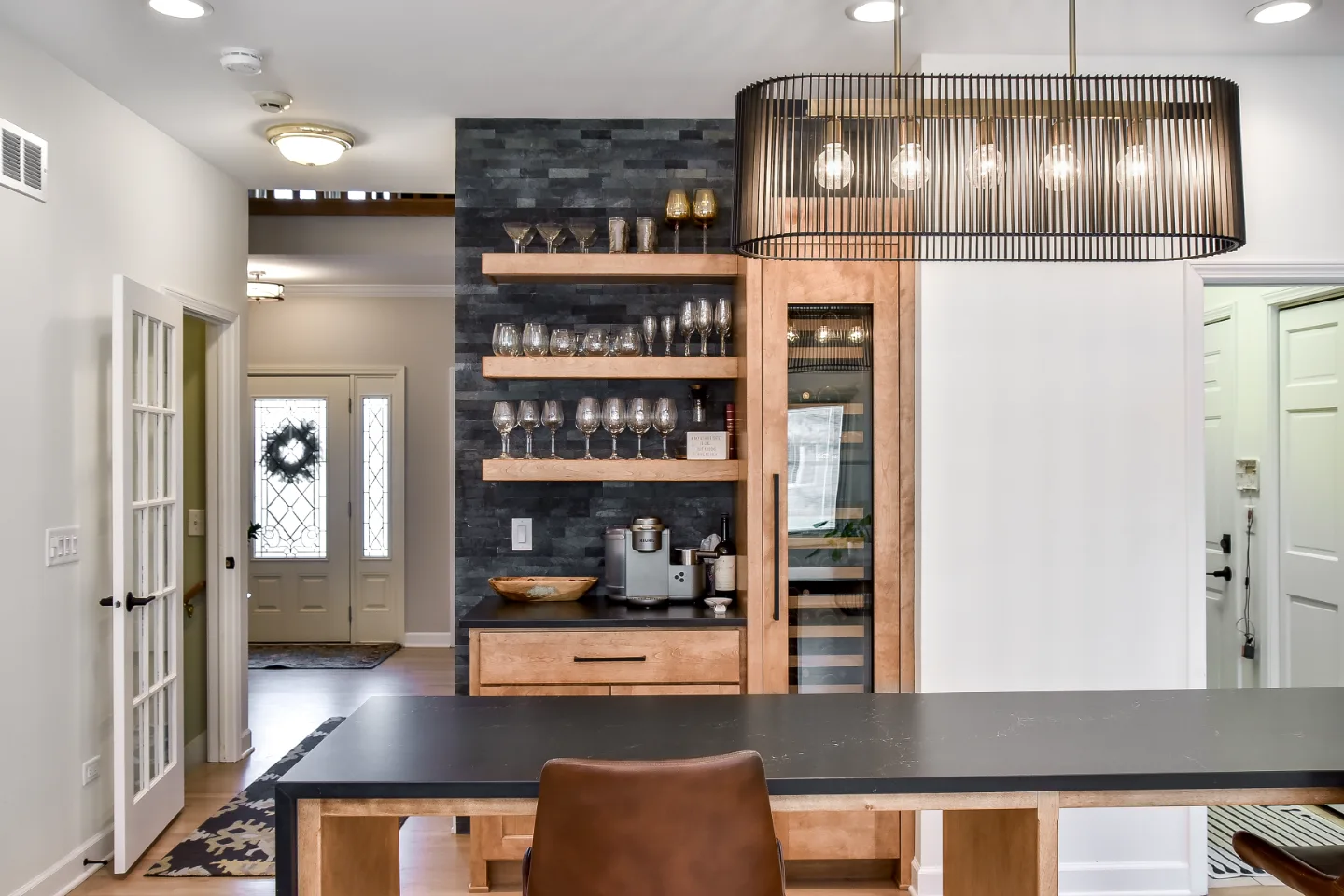 A modern-rustic home bar in Brentwood, TN. Bunker Hill Black CWP cabinetry, Cambria Colton Polished quartz, Flat Black Riverside pulls, floating shelves, and Ledger Stone Carbon backsplash by Sebring Design Build.