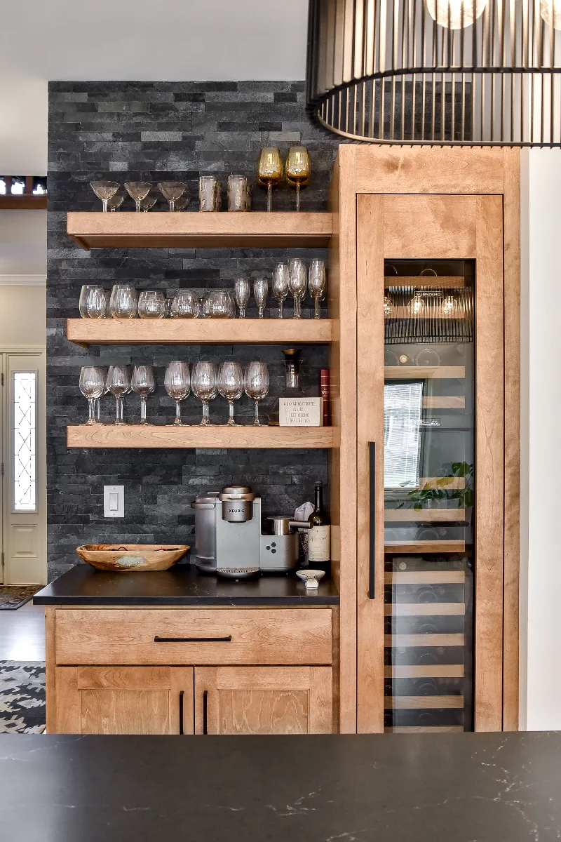 A modern-rustic home bar in Brentwood, TN. Bunker Hill Black CWP cabinetry, Cambria Colton Polished quartz, Flat Black Riverside pulls, floating shelves, and Ledger Stone Carbon backsplash by Sebring Design Build.