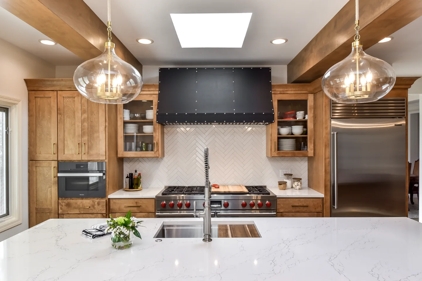 A modern-rustic kitchen in Brentwood, TN. CWP Fruitwood on Birch and Bunker Hill Black cabinetry, Cambria Charlestown Matte and Colton Polished quartz, Kohler Tournant faucet, and Ledger Stone Carbon backsplash by Sebring Design Build.