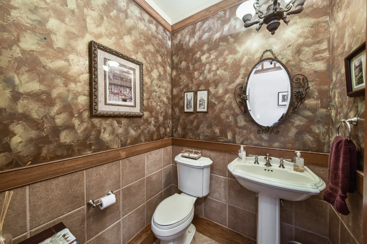 A transitional-elegant powder room in Brentwood, TN. RH Hudson Aged Brass vanity, CaesarStone Frosty Carrina quartz, Brizo Invari Luxe Gold faucet, and Serena and Lily Feather Gold wallpaper by Sebring Design Build.