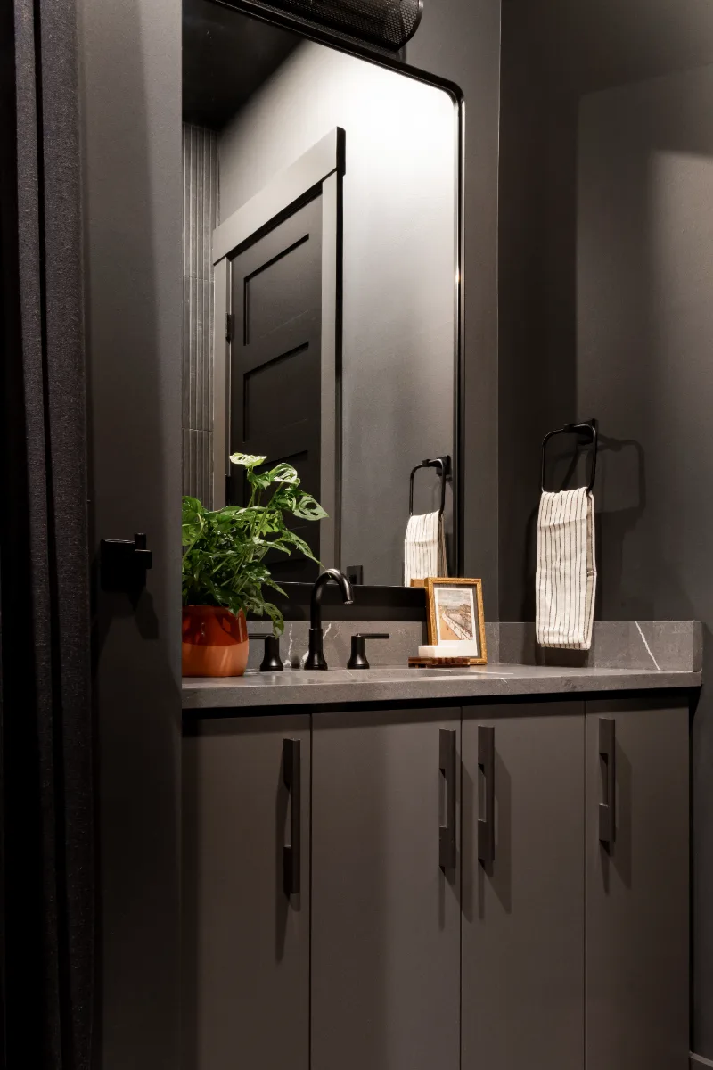 A unique-luxurious guest bath in Columbia, TN. CWP Urbane Bronze Slab cabinetry, Metro Quartz Cemento, Amerock Black Brushed Nickel, Daltile Remedy Zen shower walls, and Kenridge Ribbon Black accent tile by Sebring Design Build.