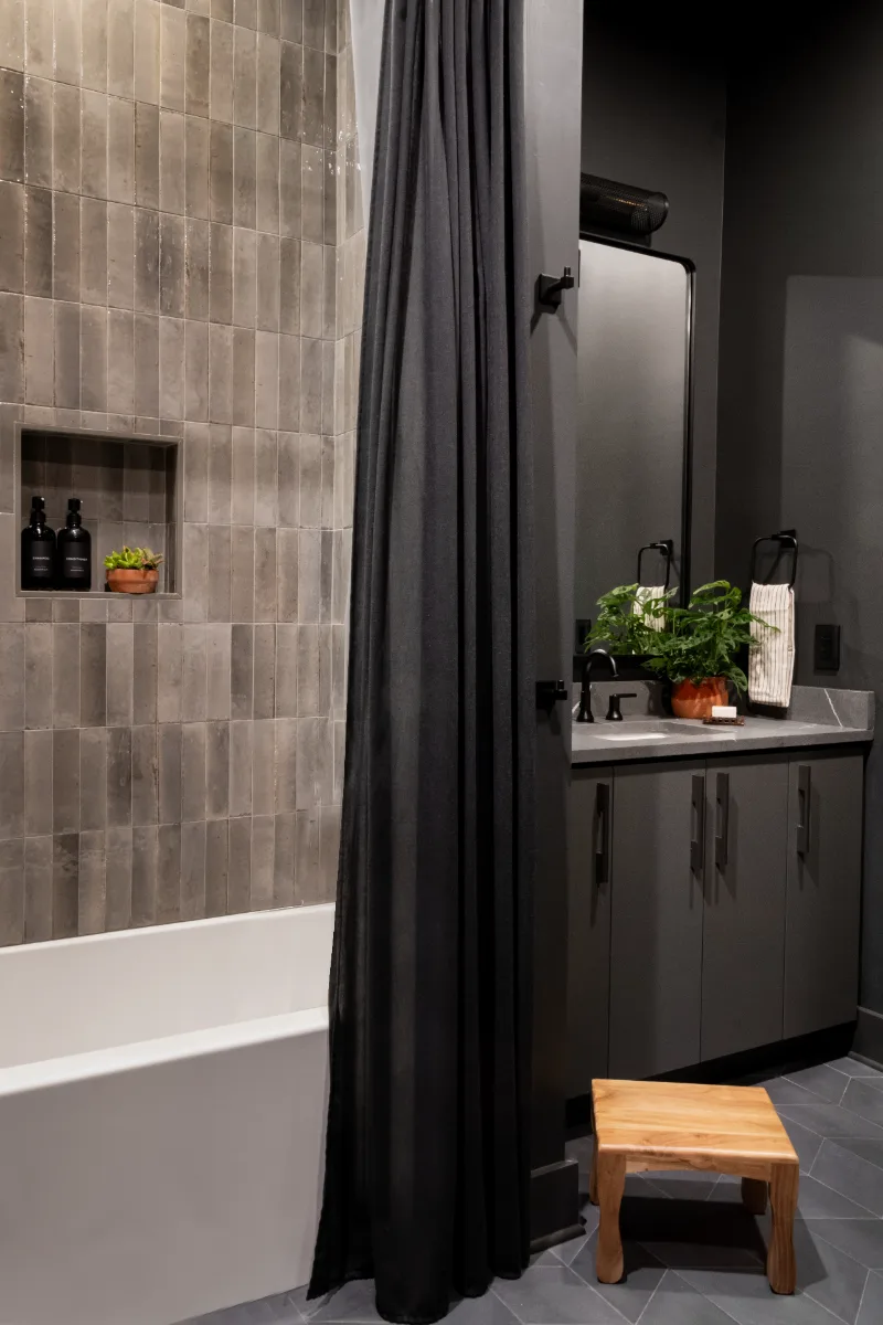A unique-luxurious guest bath in Columbia, TN. CWP Urbane Bronze Slab cabinetry, Metro Quartz Cemento, Amerock Black Brushed Nickel, Daltile Remedy Zen shower walls, and Kenridge Ribbon Black accent tile by Sebring Design Build.