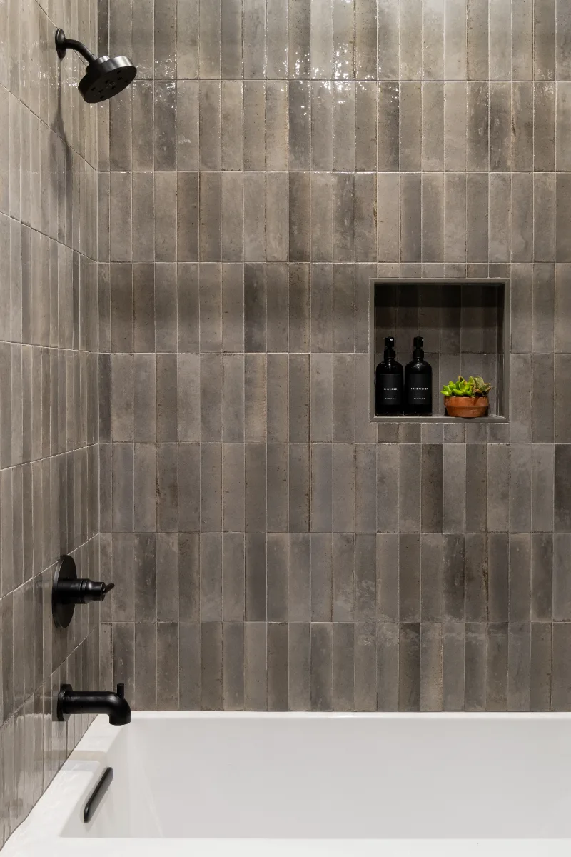 A unique-luxurious guest bath in Columbia, TN. CWP Urbane Bronze Slab cabinetry, Metro Quartz Cemento, Amerock Black Brushed Nickel, Daltile Remedy Zen shower walls, and Kenridge Ribbon Black accent tile by Sebring Design Build.