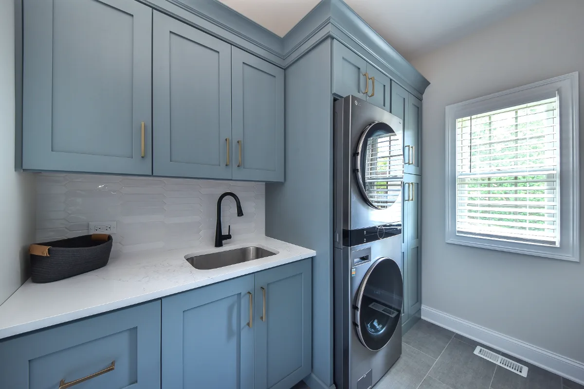 A transitional-functional laundry room in Brentwood, TN. Paint-grade Puget Sound cabinetry, CaesarStone Palm Shade honed quartz, Honey Bronze Top Knobs hardware, and Faroe Mother of Pearl flooring by Sebring Design Build.