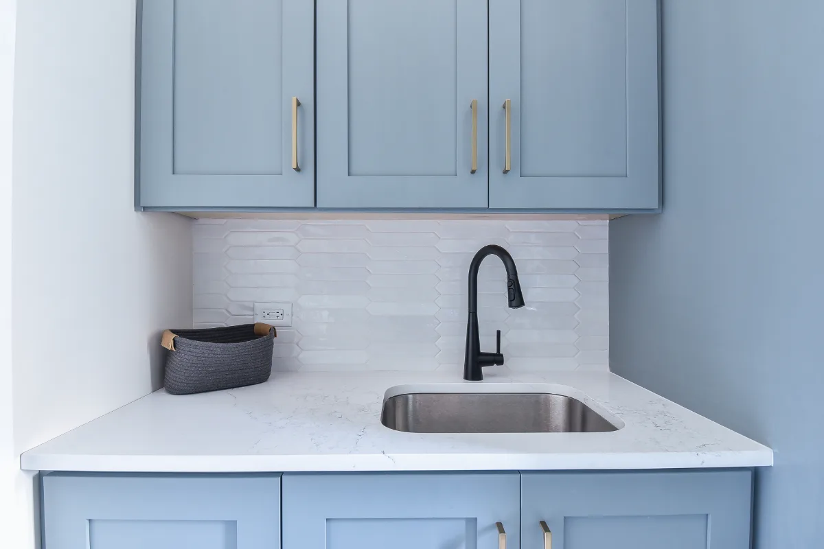 A transitional-functional laundry room in Brentwood, TN. Paint-grade Puget Sound cabinetry, CaesarStone Palm Shade honed quartz, Honey Bronze Top Knobs hardware, and Faroe Mother of Pearl flooring by Sebring Design Build.