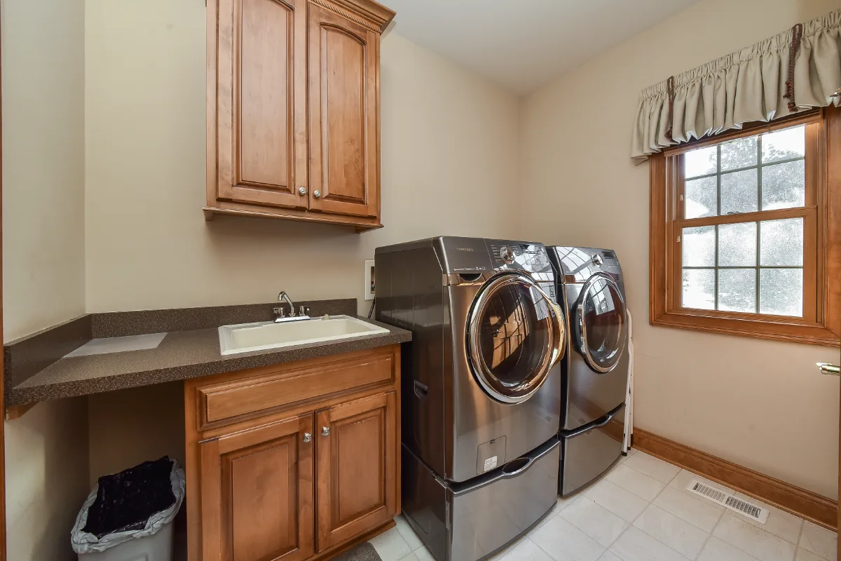 A transitional-functional laundry room in Brentwood, TN. Paint-grade Puget Sound cabinetry, CaesarStone Palm Shade honed quartz, Honey Bronze Top Knobs hardware, and Faroe Mother of Pearl flooring by Sebring Design Build.