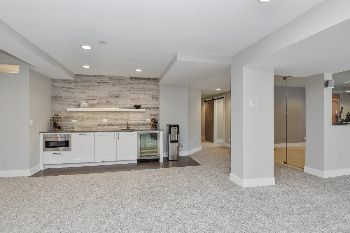 A functional-modern basement bar in Franklin, TN. Bishop Glacier White cabinetry, Cambria Devon quartz, Delta Trinsic Arctic Stainless sink, and Magnifica Silver backsplash by Sebring Design Build.