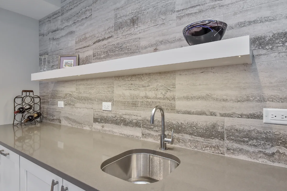 A functional-modern basement bar in Franklin, TN. Bishop Glacier White cabinetry, Cambria Devon quartz, Delta Trinsic Arctic Stainless sink, and Magnifica Silver backsplash by Sebring Design Build.