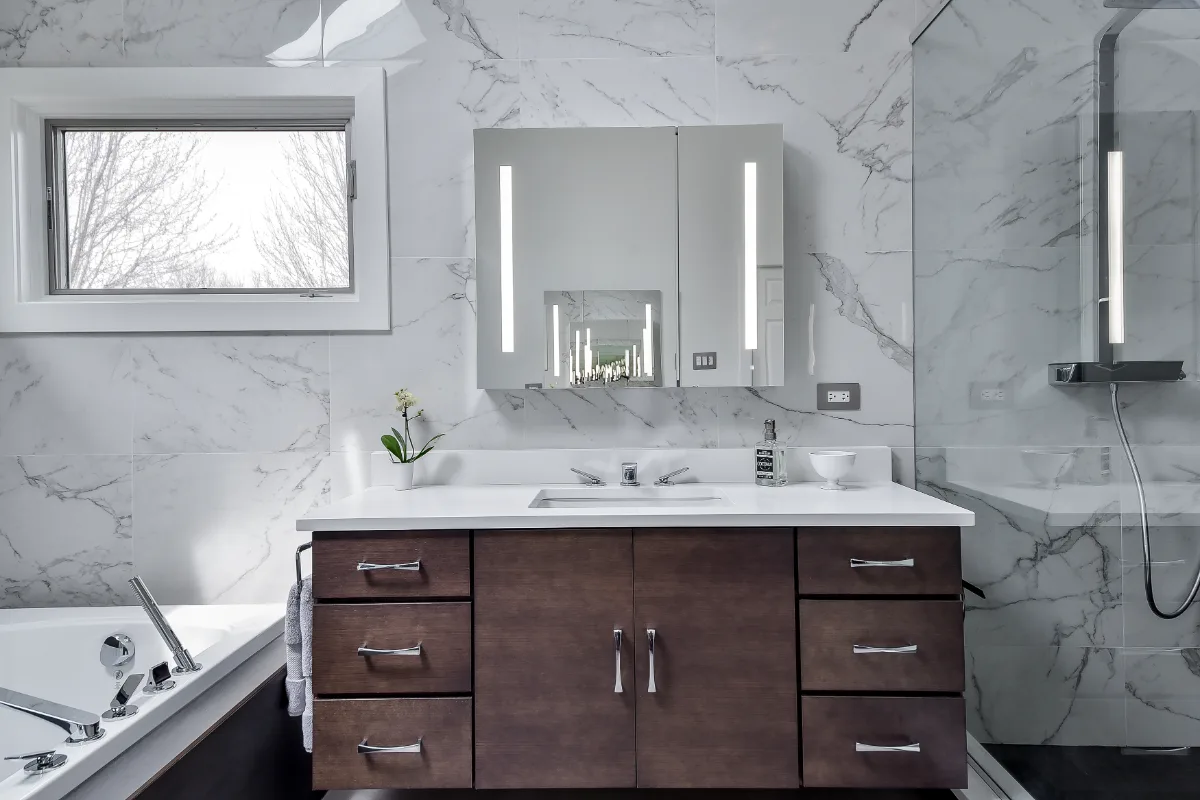 A modern-crisp primary bath remodel in Brentwood, TN. Wellborn Barcelona Oak Drift cabinetry, Orion Absolute White quartz, Atlas Concorde Calacatta Extra vanity wall, and Polished Chrome fixtures by Sebring Design Build.