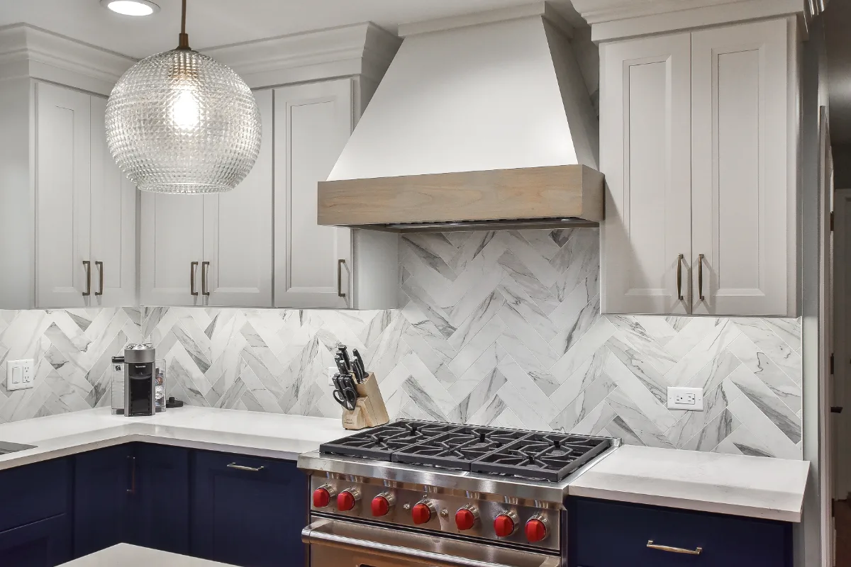 A modern-coastal kitchen remodel in Brentwood, TN. Two-tone cabinetry in Soft White and Midnight, Caesarstone Calacatta Nuvo, and Matte Black fixtures by Sebring Design Build.