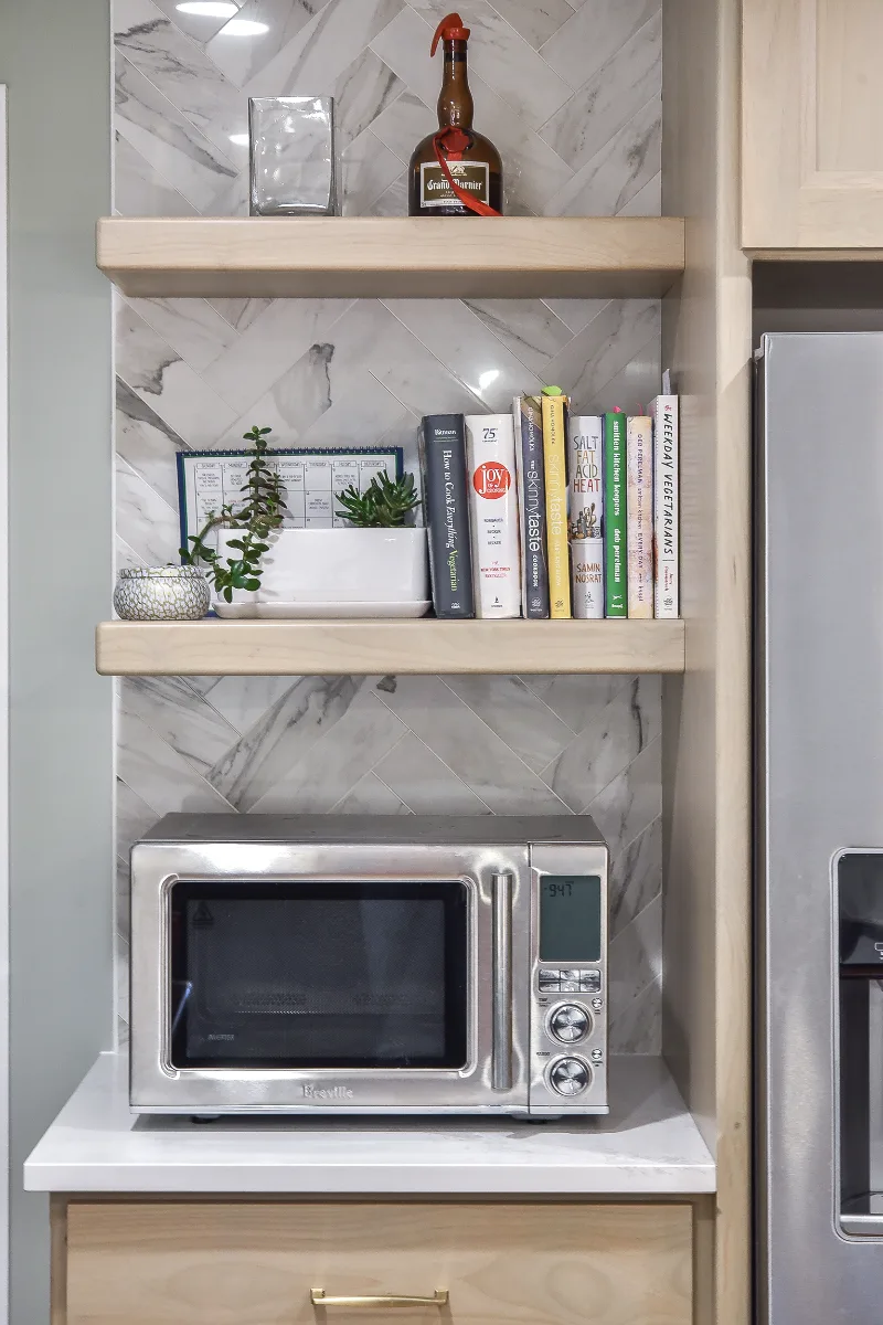 A modern-coastal kitchen remodel in Brentwood, TN. Two-tone cabinetry in Soft White and Midnight, Caesarstone Calacatta Nuvo, and Matte Black fixtures by Sebring Design Build.