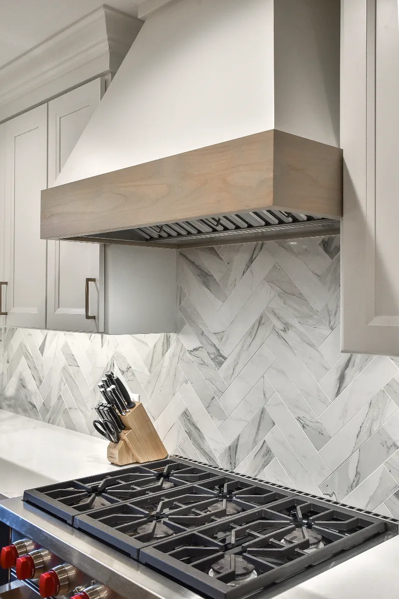 A modern-coastal kitchen remodel in Brentwood, TN. Two-tone cabinetry in Soft White and Midnight, Caesarstone Calacatta Nuvo, and Matte Black fixtures by Sebring Design Build.