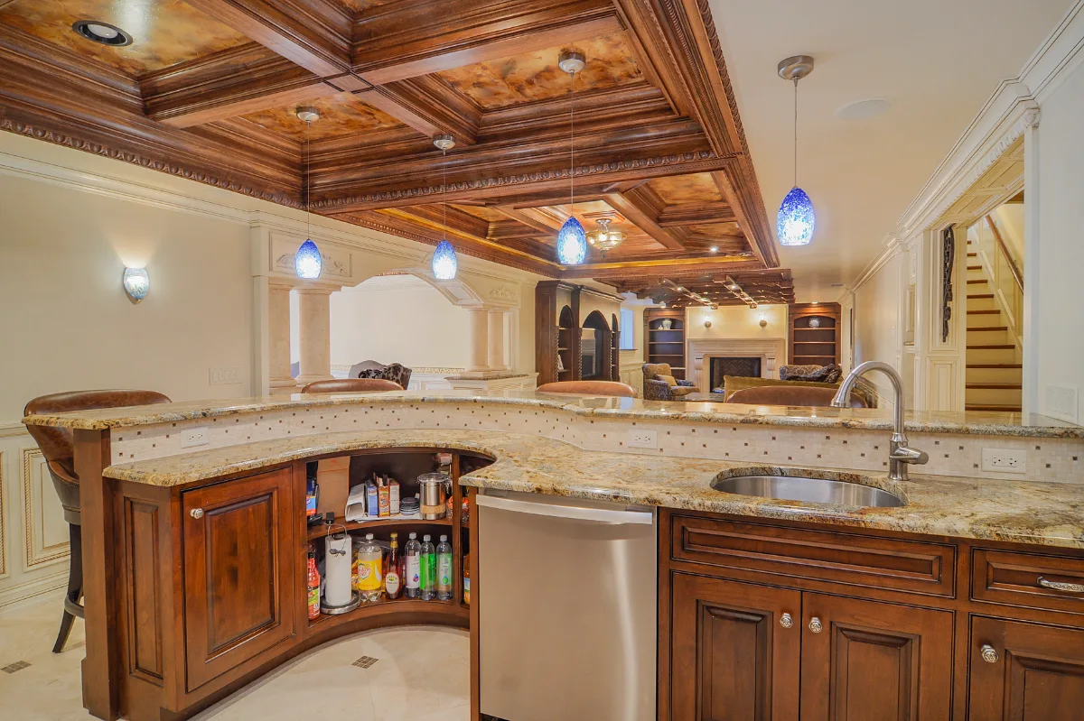 A traditional-intricate basement remodel in Franklin, TN. Coffered ceiling, custom carpentry, built-in entertainment unit, fireplace, bar, guest bath, gym, and dining room by Sebring Design Build.