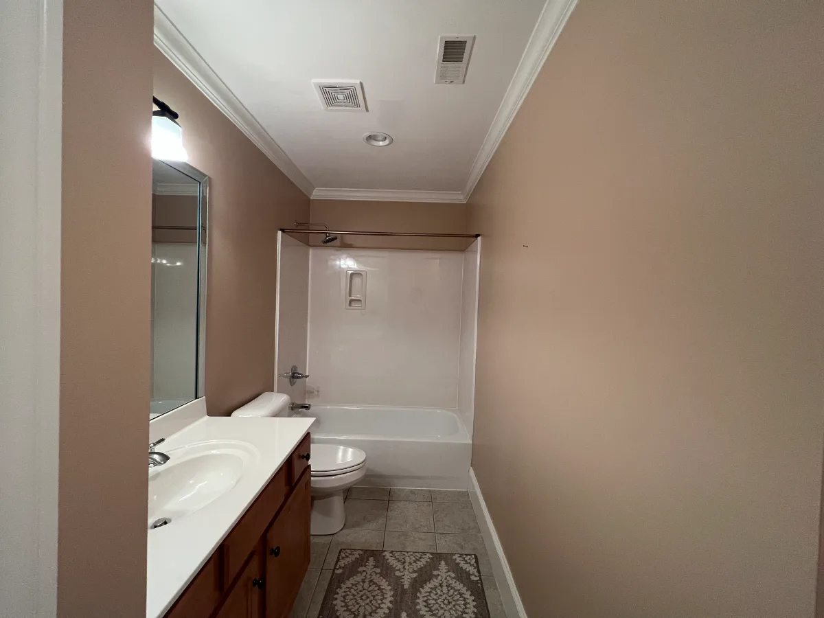 A modern-elegant guest bath (HER) in Watkins Creek, Franklin TN 37067. White Oak Tatami cabinetry, Mikado Calacatta Tree quartz, Iris Venezia Beige shower walls, and Delta Trinsic Champagne Bronze by Sebring Design Build.