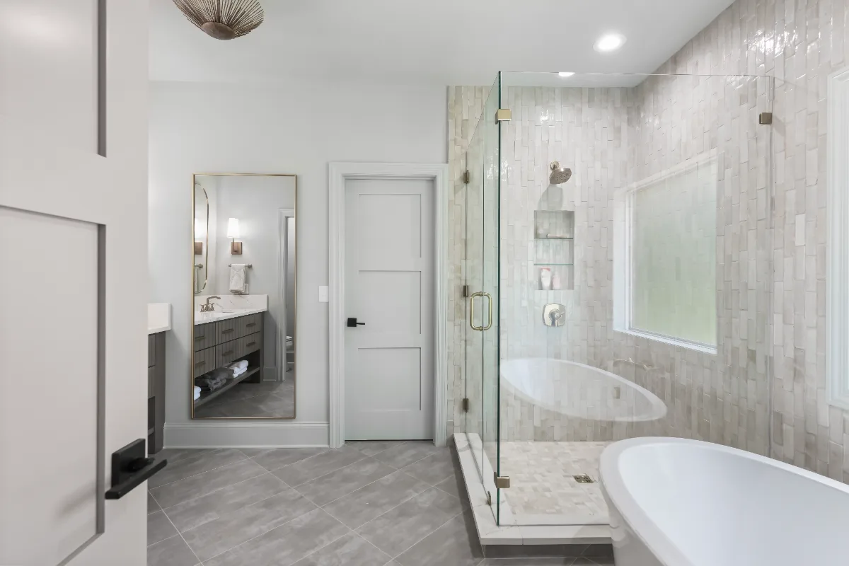 A modern-elegant primary bath in Watkins Creek, Franklin TN 37067. White Oak Flint Hills cabinetry, Mikado Calacatta Tree quartz, MTI freestanding tub, and Natural White Zellige shower walls by Sebring Design Build.