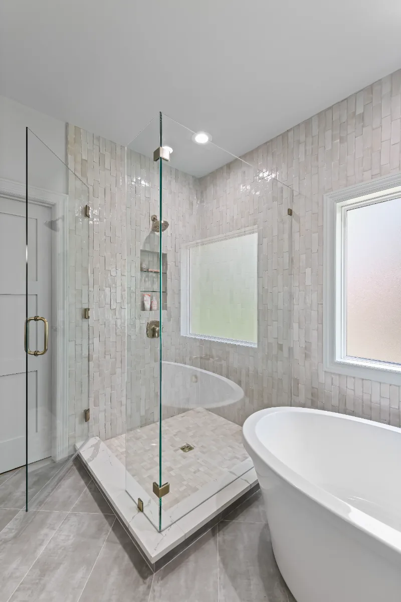 A modern-elegant primary bath in Watkins Creek, Franklin TN 37067. White Oak Flint Hills cabinetry, Mikado Calacatta Tree quartz, MTI freestanding tub, and Natural White Zellige shower walls by Sebring Design Build.