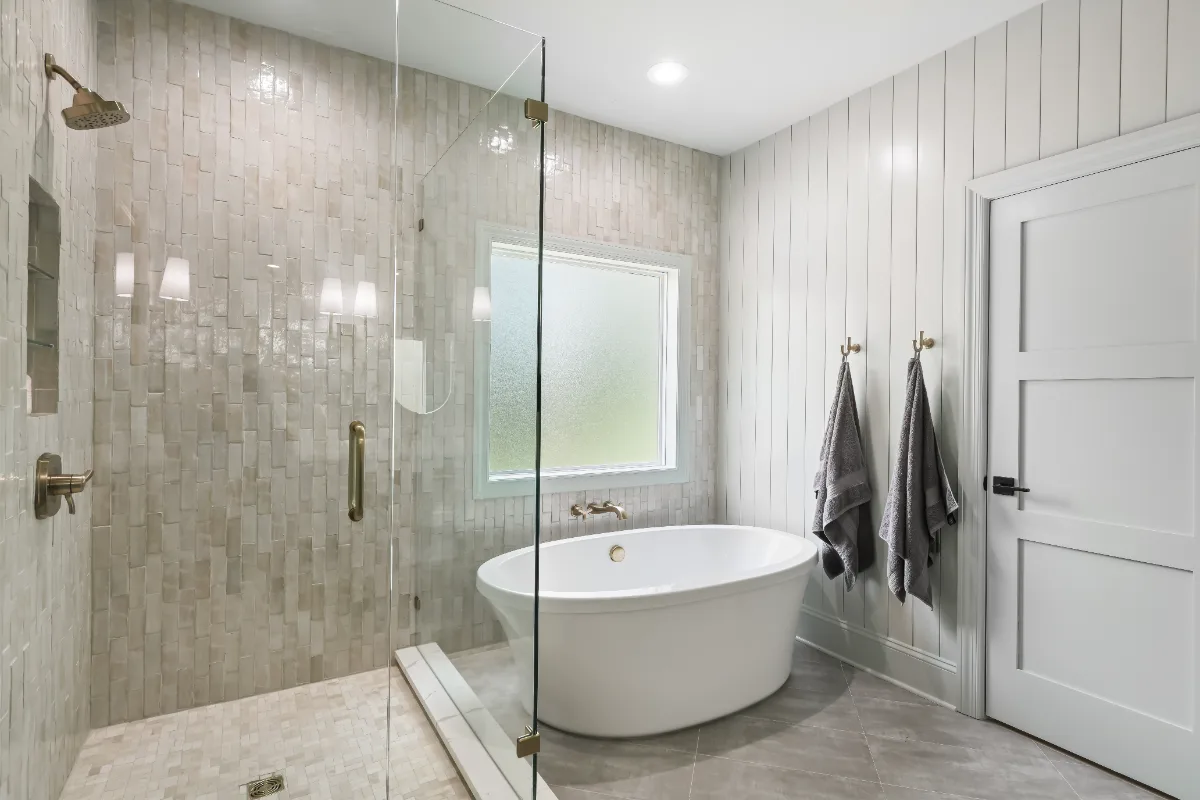 A modern-elegant primary bath in Watkins Creek, Franklin TN 37067. White Oak Flint Hills cabinetry, Mikado Calacatta Tree quartz, MTI freestanding tub, and Natural White Zellige shower walls by Sebring Design Build.