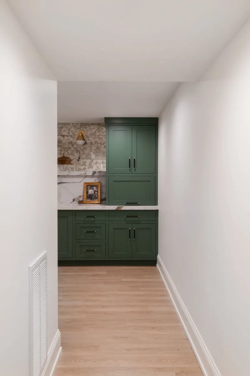 A modern-functional basement kitchenette in Bonbrook, Brentwood TN 37027. Kilimanjaro quartz with mitered edge, Patina Siren Mirror glass backsplash, and Delta Matte Black fixtures by Sebring Design Build.