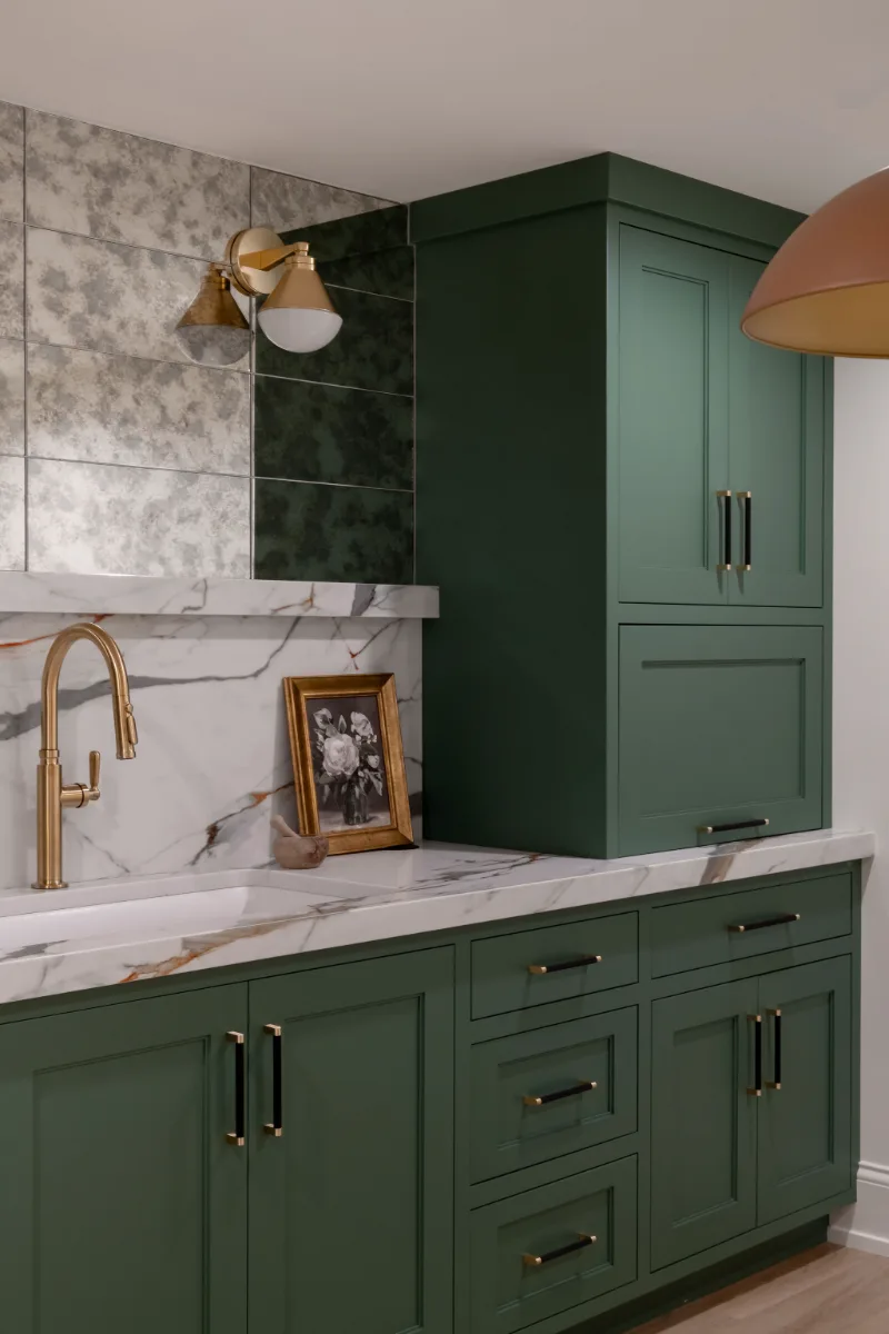 A modern-functional basement kitchenette in Bonbrook, Brentwood TN 37027. Kilimanjaro quartz with mitered edge, Patina Siren Mirror glass backsplash, and Delta Matte Black fixtures by Sebring Design Build.